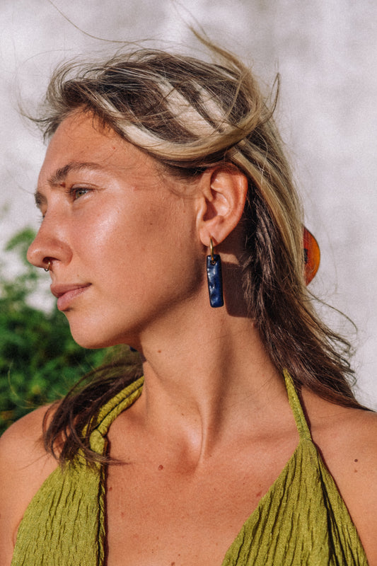 Penha handmade ceramic earrings in Blue Navy — minimalist rectangular drop worn on blond hair model, sculpted clay, made in Lisbon Portugal by Jadeo Studio