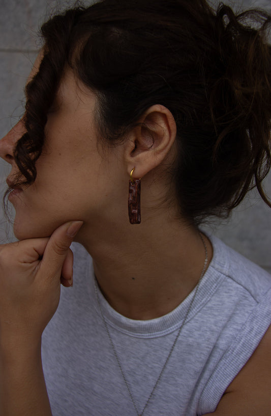 Penha handmade ceramic earrings in Burgundy worn by curly hair model — minimalist rectangular drop, sculpted clay, made in Lisbon Portugal by Jadeo Studio