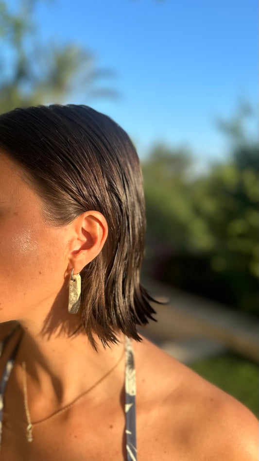 Penha handmade ceramic earrings in Sparkling White, worn by brown hair model and beautiful sunlight — minimalist rectangular drop, sculpted clay, made in Lisbon Portugal by Jadeo Studio