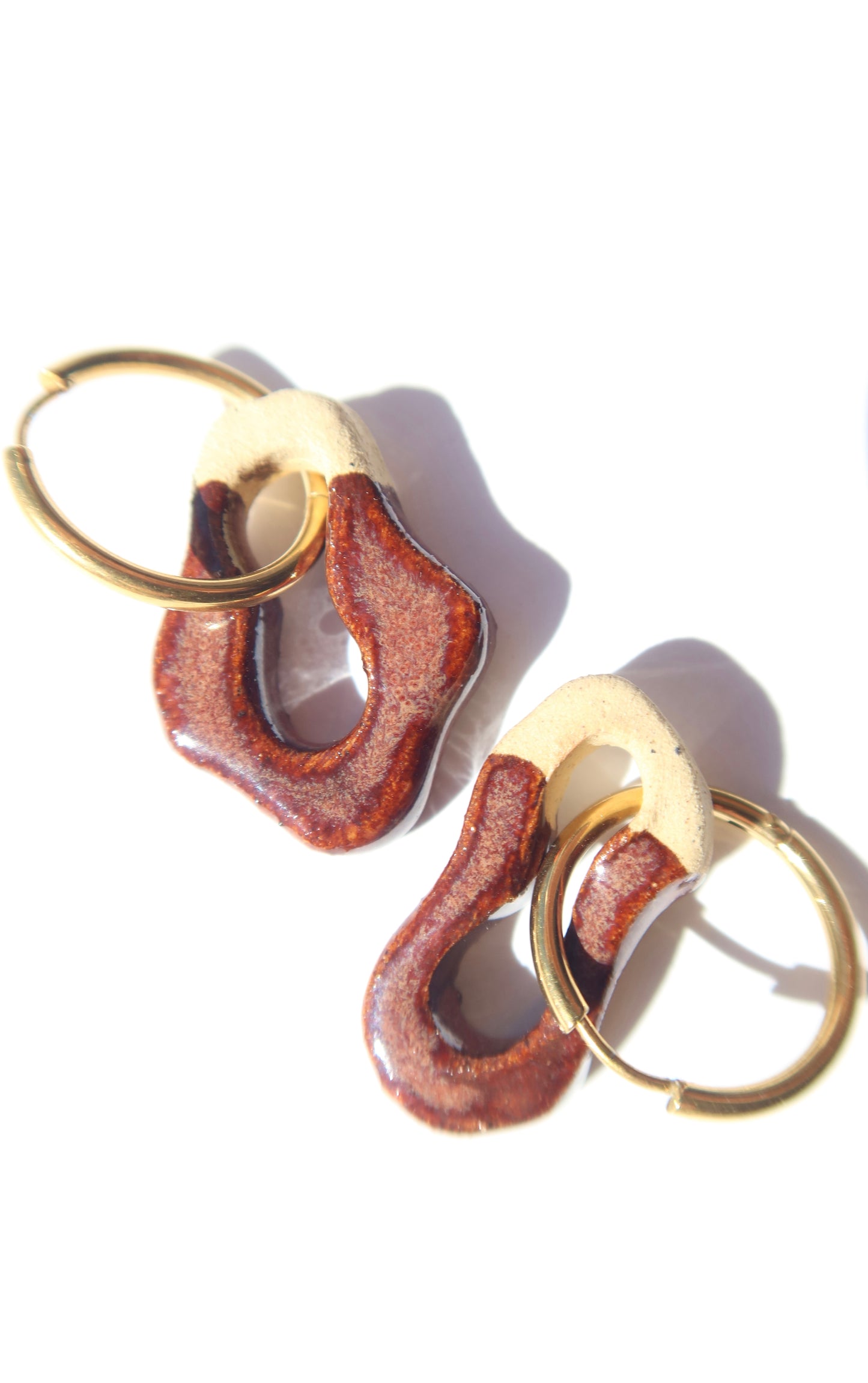 Close-up of Mosca burgundy ceramic earrings — glossy glazed surface and organic clay texture, handmade in Portugal