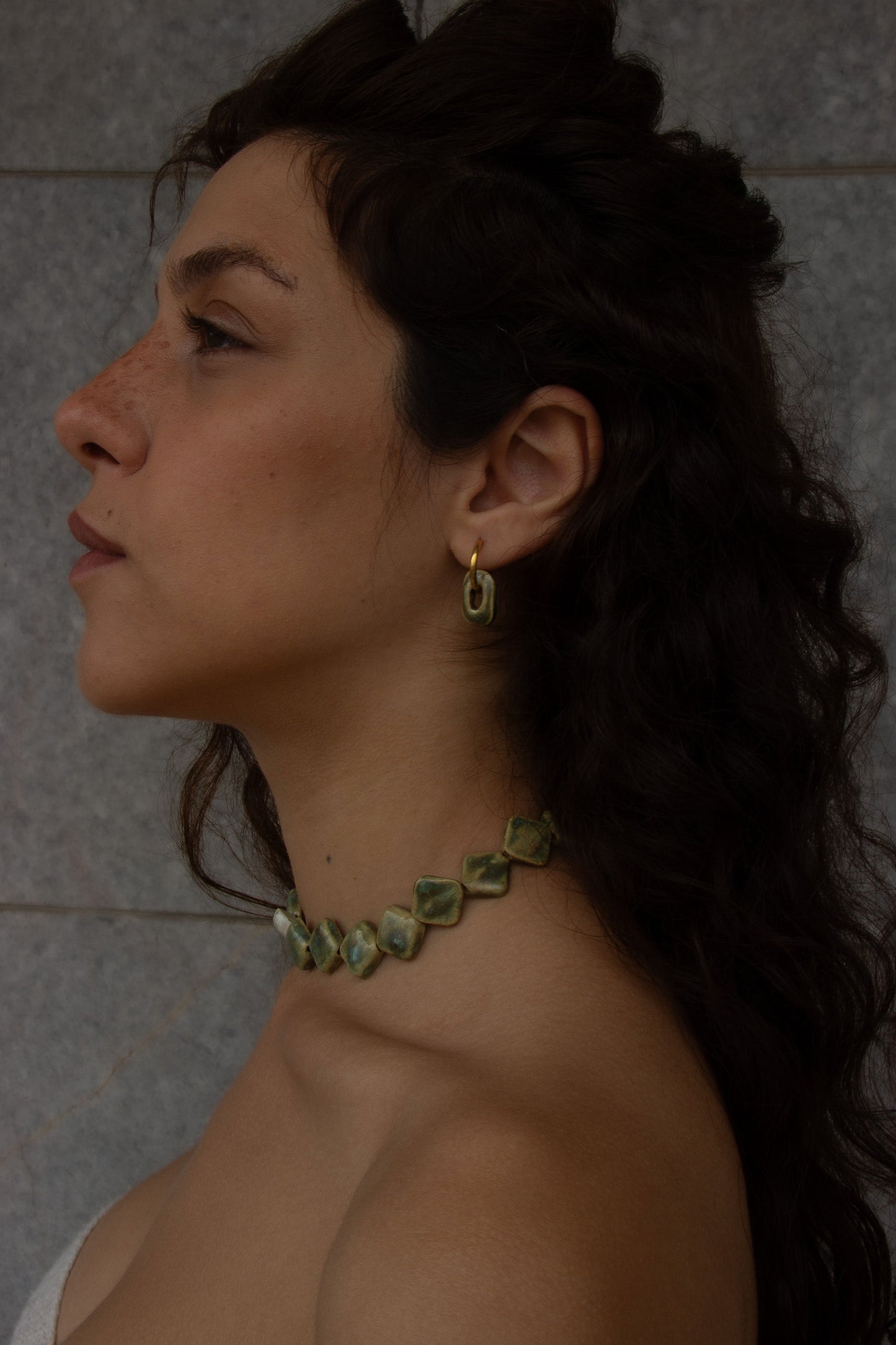Azoia handmade ceramic earrings in Light Green worn by curly hair model — subtle small hoop, everyday elegance, made in Lisbon Portugal by Jadeo Studio