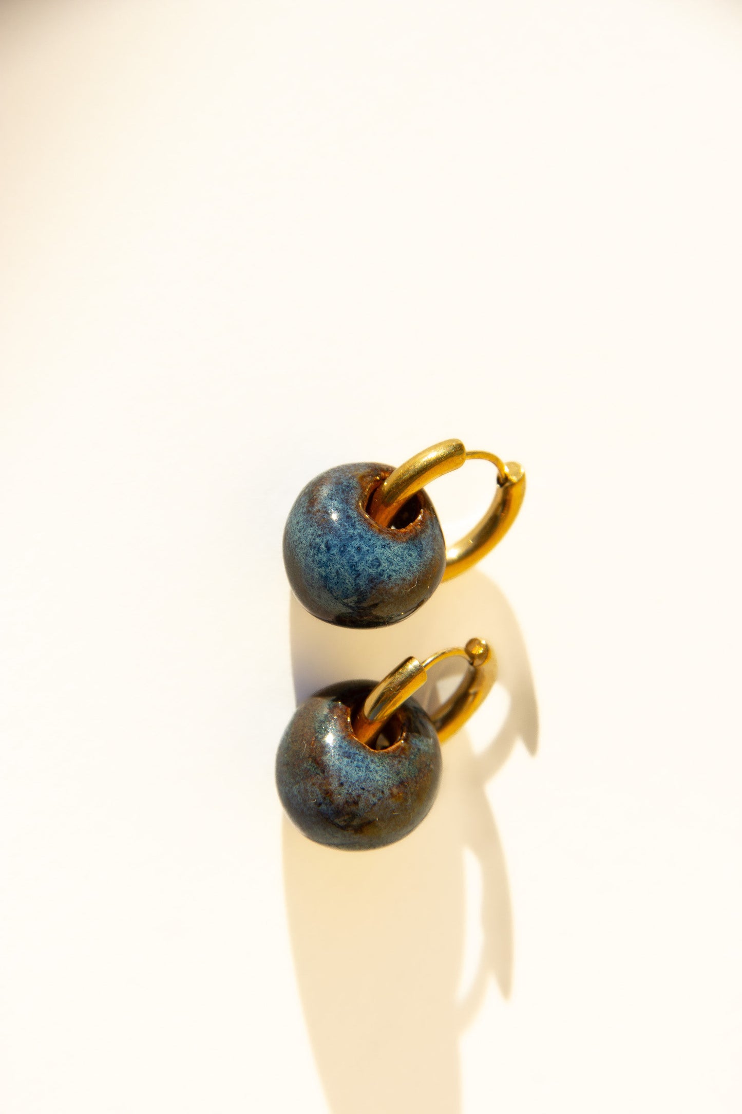 Gomes handmade ceramic earrings in Blue Jeans, glossy glaze — rounded circular form, bold yet discreet, soft denim blue glaze, made in Lisbon Portugal by Jadeo Studio