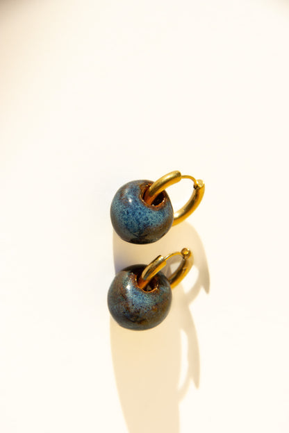 Gomes handmade ceramic earrings in Blue Jeans, glossy glaze — rounded circular form, bold yet discreet, soft denim blue glaze, made in Lisbon Portugal by Jadeo Studio
