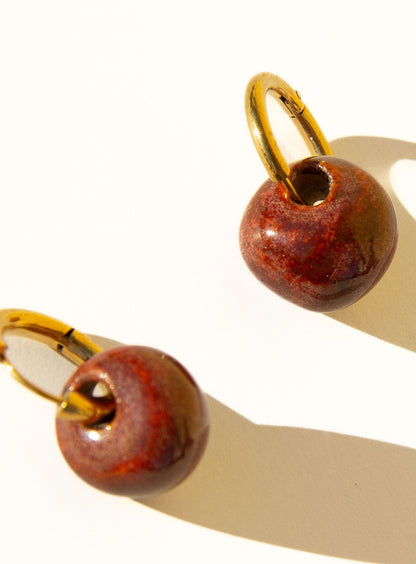 Gomes handmade ceramic earrings in Burgundy, glossy glaze — rounded circular form, bold yet discreet, deep wine red glaze, made in Lisbon Portugal by Jadeo Studio