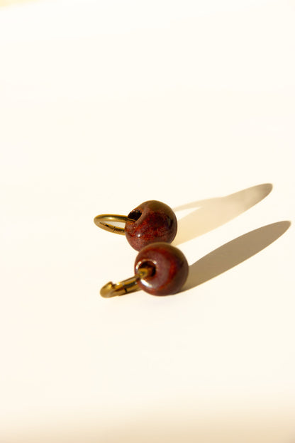 Gomes handmade ceramic earrings in Burgundy — rounded circular form, bold yet discreet, deep wine red glaze, statement jewelry made in Lisbon Portugal by Jadeo Studio