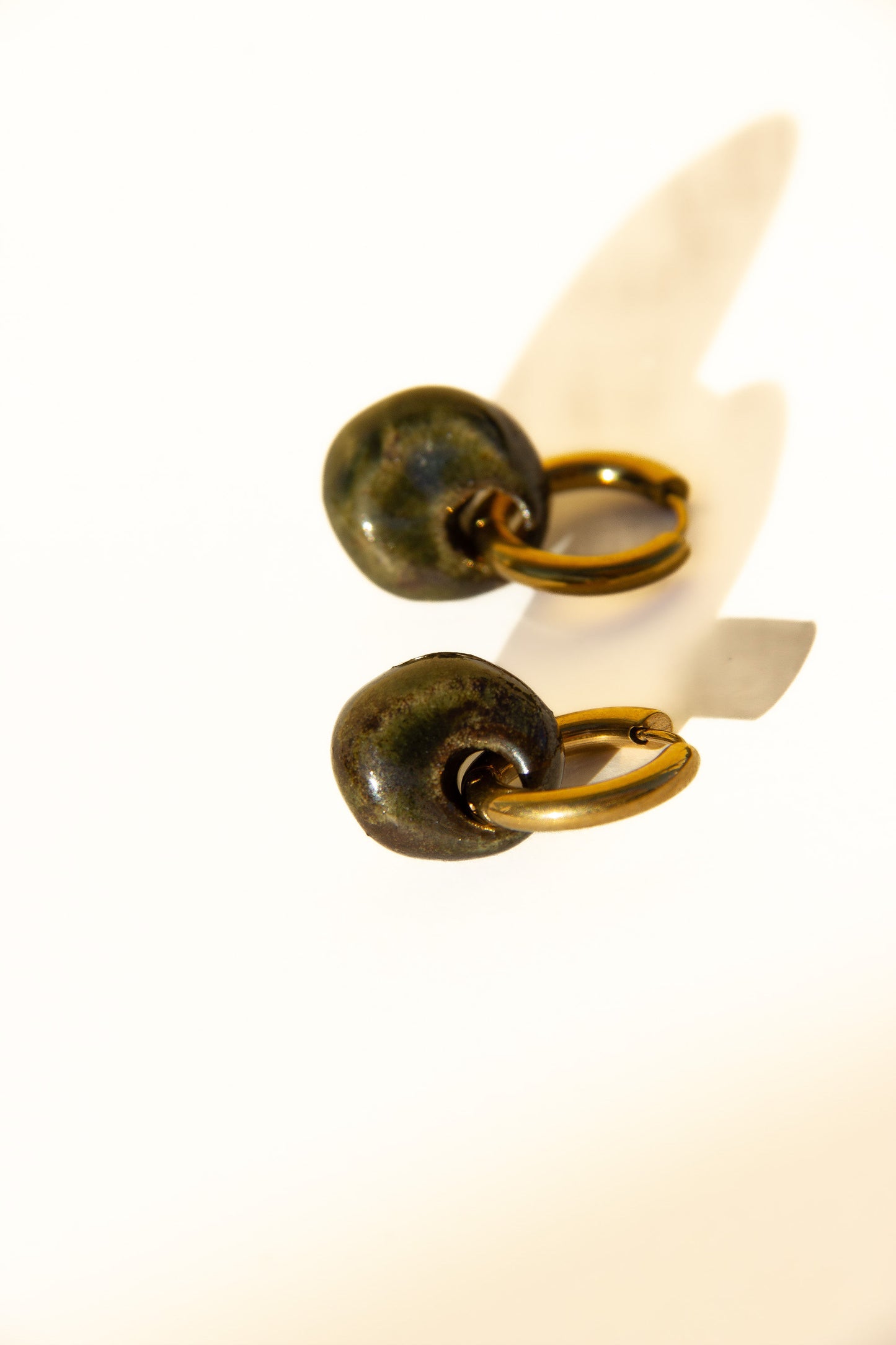 Gomes handmade ceramic earrings in Dark Green — rounded circular form, bold yet discreet, deep forest green glaze, made in Lisbon Portugal by Jadeo Studio