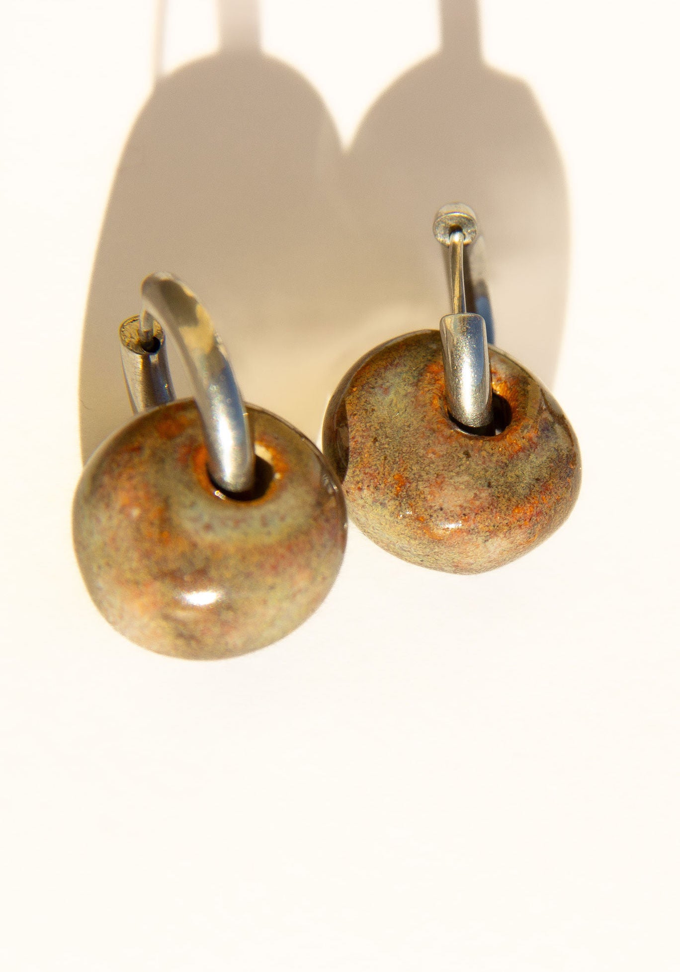 Gomes handmade ceramic earrings in Grey Green — rounded circular form, bold yet discreet, muted green-grey glaze, made in Lisbon Portugal by Jadeo Studio, silver and gold hoop