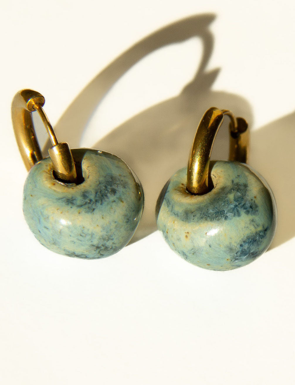 Gomes handmade ceramic earrings in Sparkling Blue, glossy glaze — rounded circular form, bold yet discreet, made in Lisbon Portugal by Jadeo Studio