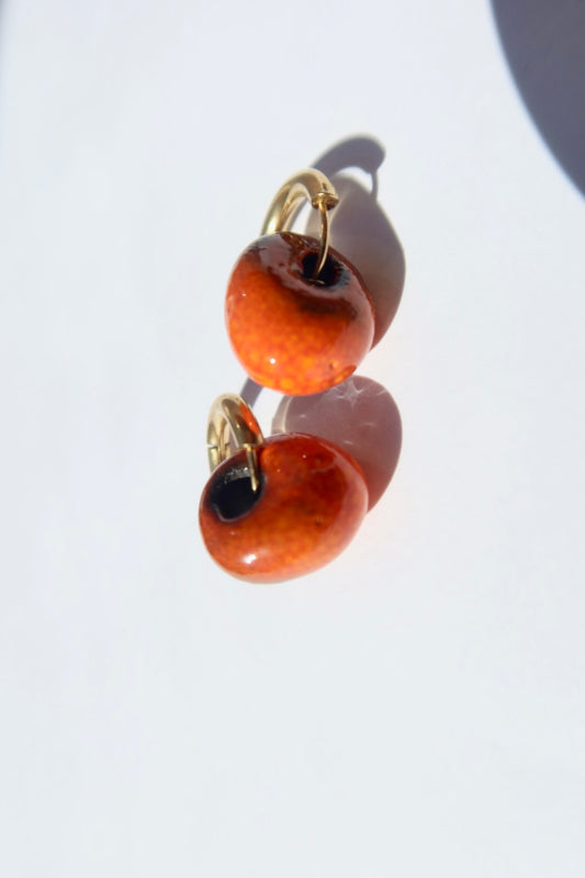 Gomes handmade ceramic earrings in Volcano on Dark Clay — rounded circular form, bold yet discreet, warm earthy glaze, made in Lisbon Portugal by Jadeo Studio