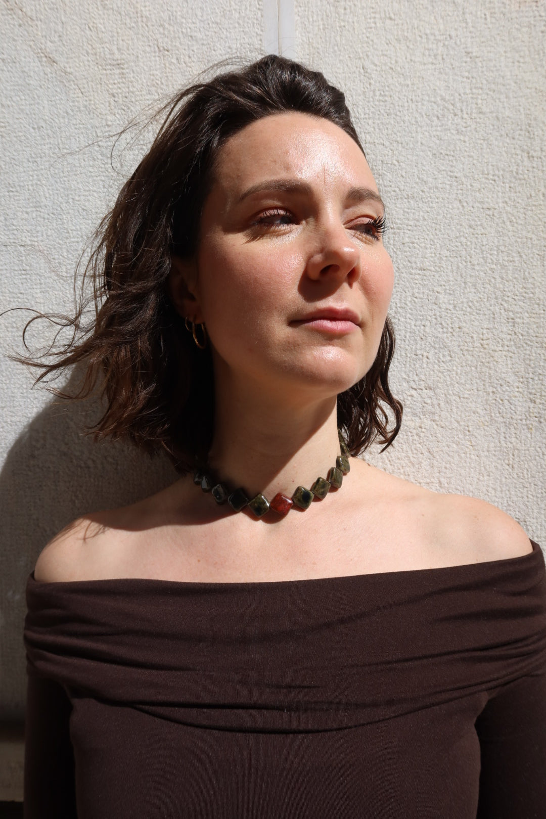 Monti handmade ceramic choker necklace in Dark Green and Burgundy worn by curly hair model — sculptural beads inspired by Roman architecture, made in Lisbon Portugal by Jadeo Studio