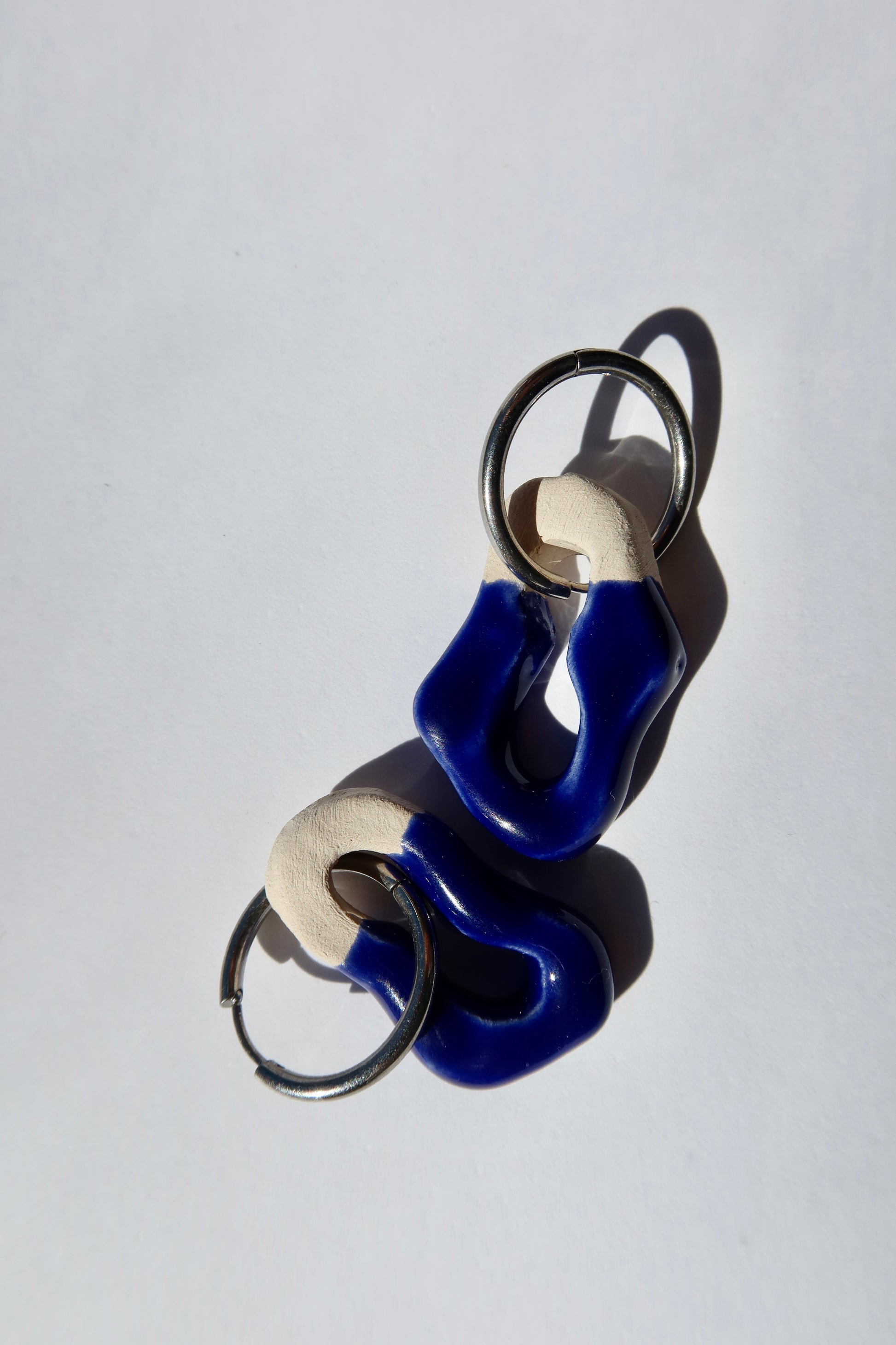 Mosca blue navy ceramic earrings arranged vertically — handmade organic sculpted clay with glossy glaze, contemporary jewelry made in Lisbon Portugal by Jadeo Studio