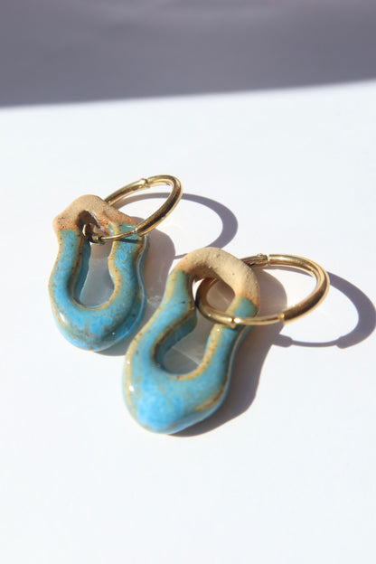 Mosca handmade ceramic earrings in Blue Sky — organic sculpted clay with glossy glaze, pair displayed in natural sunlight with soft shadow, made in Lisbon Portugal by Jadeo Studio - silver and gold hoop