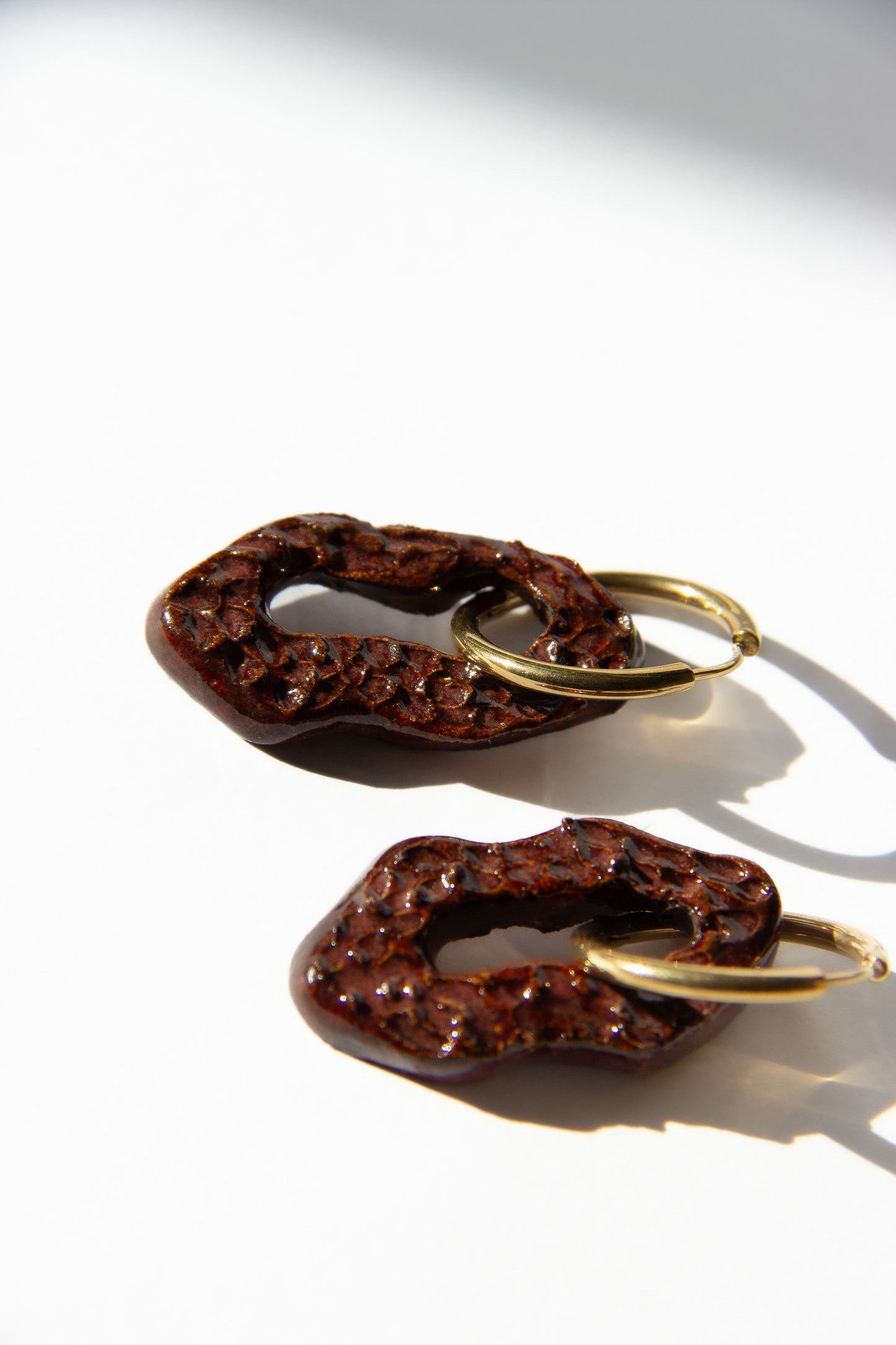 Mosca handmade ceramic earrings in Dotted Burgundy — organic sculpted clay with glossy glaze and dotted texture, made in Lisbon Portugal by Jadeo Studio, silver and gold hoop