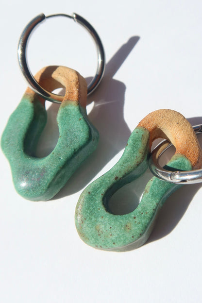 Close-up of Mosca green mat ceramic earrings — organic sculpted clay with glossy glaze and raw texture contrast, handmade in Lisbon Portugal by Jadeo Studio