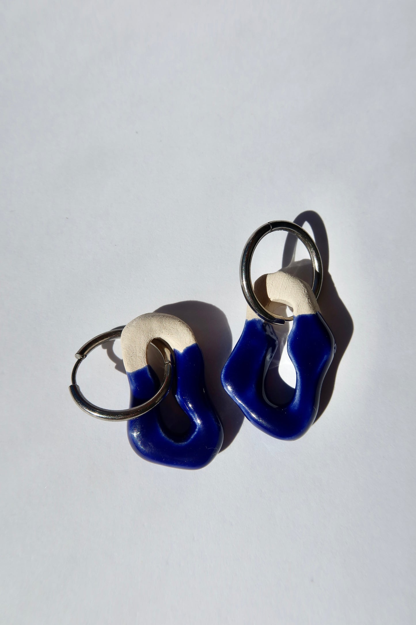 Mosca handmade ceramic earrings in blue navy — sculptural clay design with glossy finish, minimalist composition in natural light, made in Lisbon Portugal by Jadeo Studio