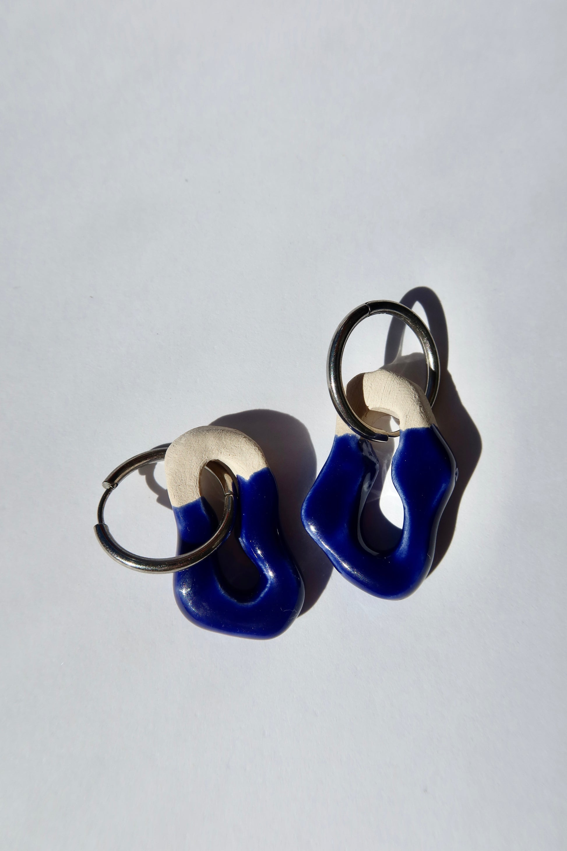 Mosca handmade ceramic earrings in blue navy — sculptural clay design with glossy finish, minimalist composition in natural light, made in Lisbon Portugal by Jadeo Studio