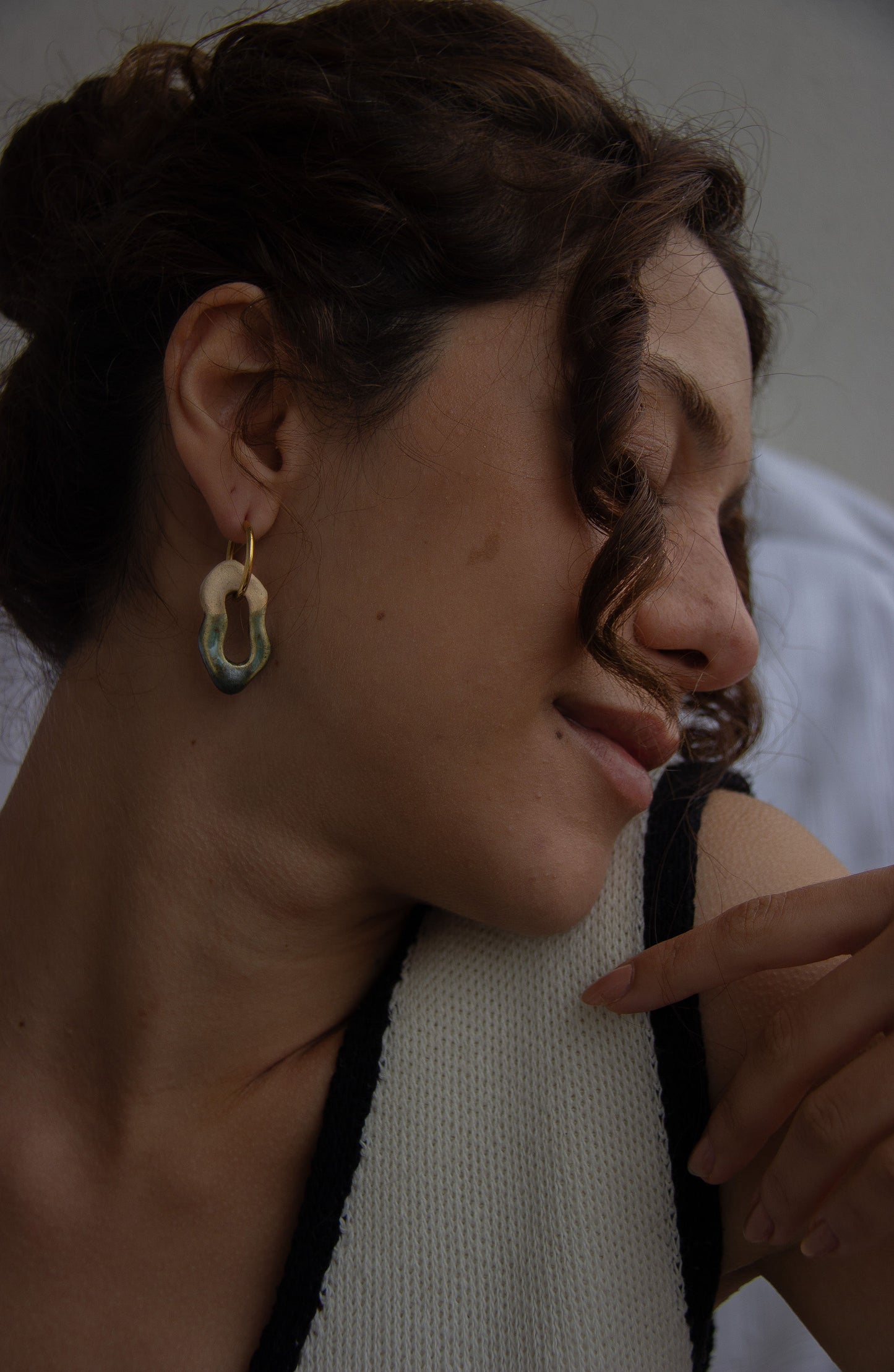 Mosca handmade ceramic earrings in Light Green worn by curly hair model — organic sculpted clay with glossy glaze, made in Lisbon Portugal by Jadeo Studio