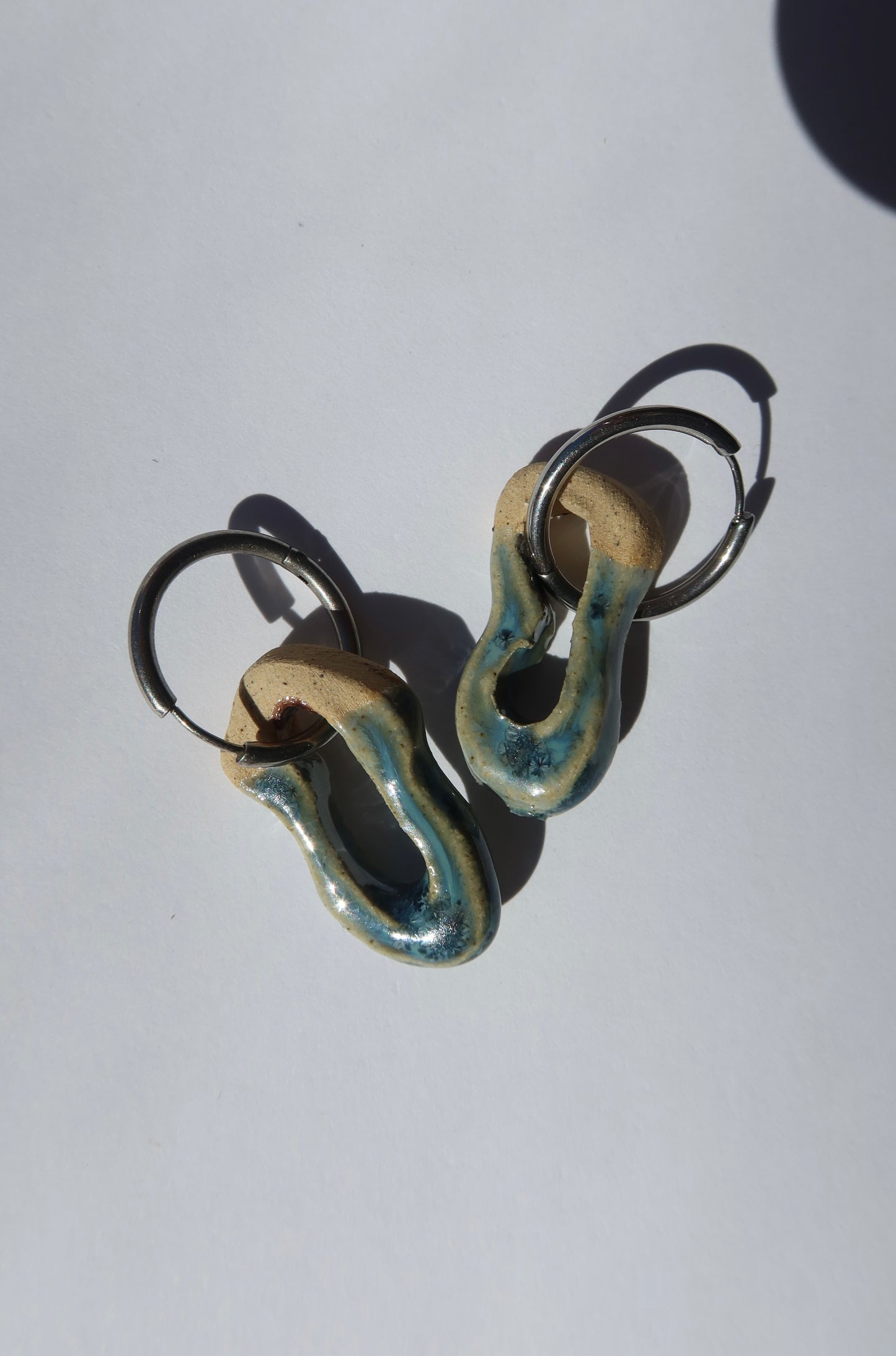 Close-up of Mosca sparkling blue ceramic earrings — glossy glazed surface and organic sculpted clay texture, handmade in Lisbon Portugal by Jadeo Studio
