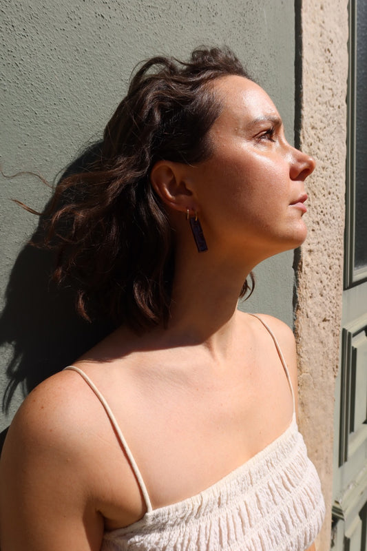 Penha handmade ceramic earrings in Aubergine worn by short curly hair model — minimalist rectangular drop, sculpted clay, made in Lisbon Portugal by Jadeo Studio