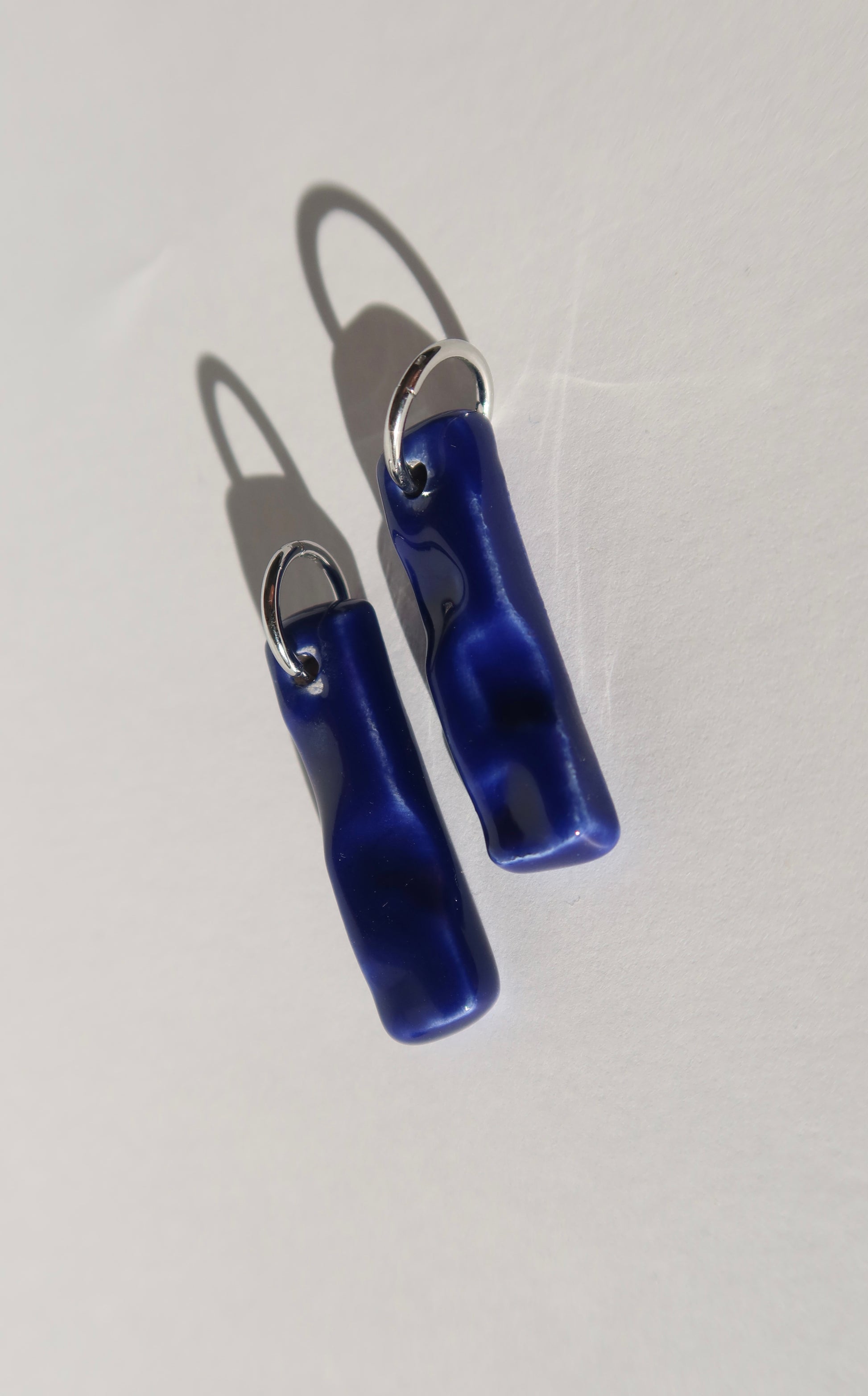 Penha handmade ceramic earrings in Blue Navy — minimalist rectangular drop, sculpted clay, made in Lisbon Portugal by Jadeo Studio, silver and gold hoop