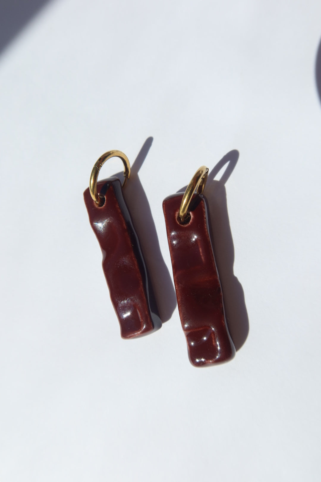 Penha handmade ceramic earrings in Brown Red, glossy glaze — minimalist rectangular drop, sculpted clay, made in Lisbon Portugal by Jadeo Studio