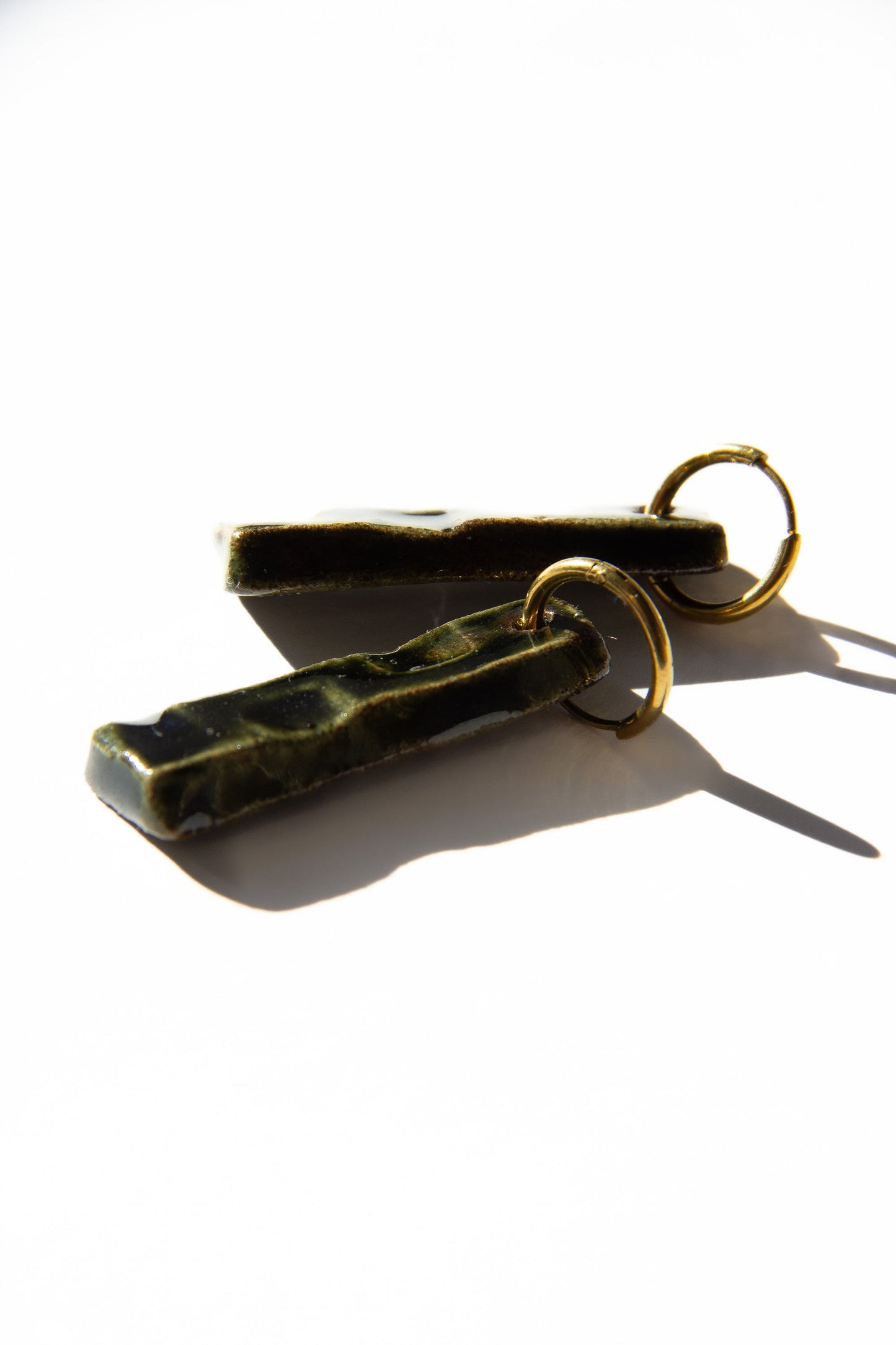 Penha handmade ceramic earrings in Dark Green, glossy glaze — minimalist rectangular drop, sculpted clay, made in Lisbon Portugal by Jadeo Studio