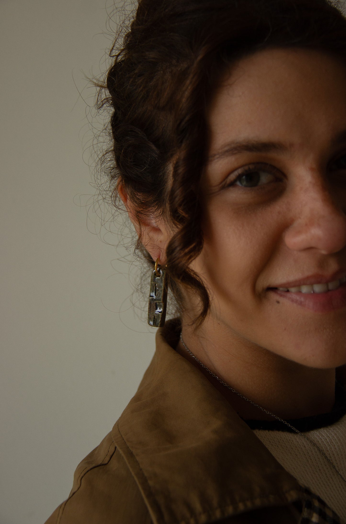 Penha handmade ceramic earrings in Dark Green, worn by curly hair model — minimalist rectangular drop, sculpted clay, made in Lisbon Portugal by Jadeo Studio