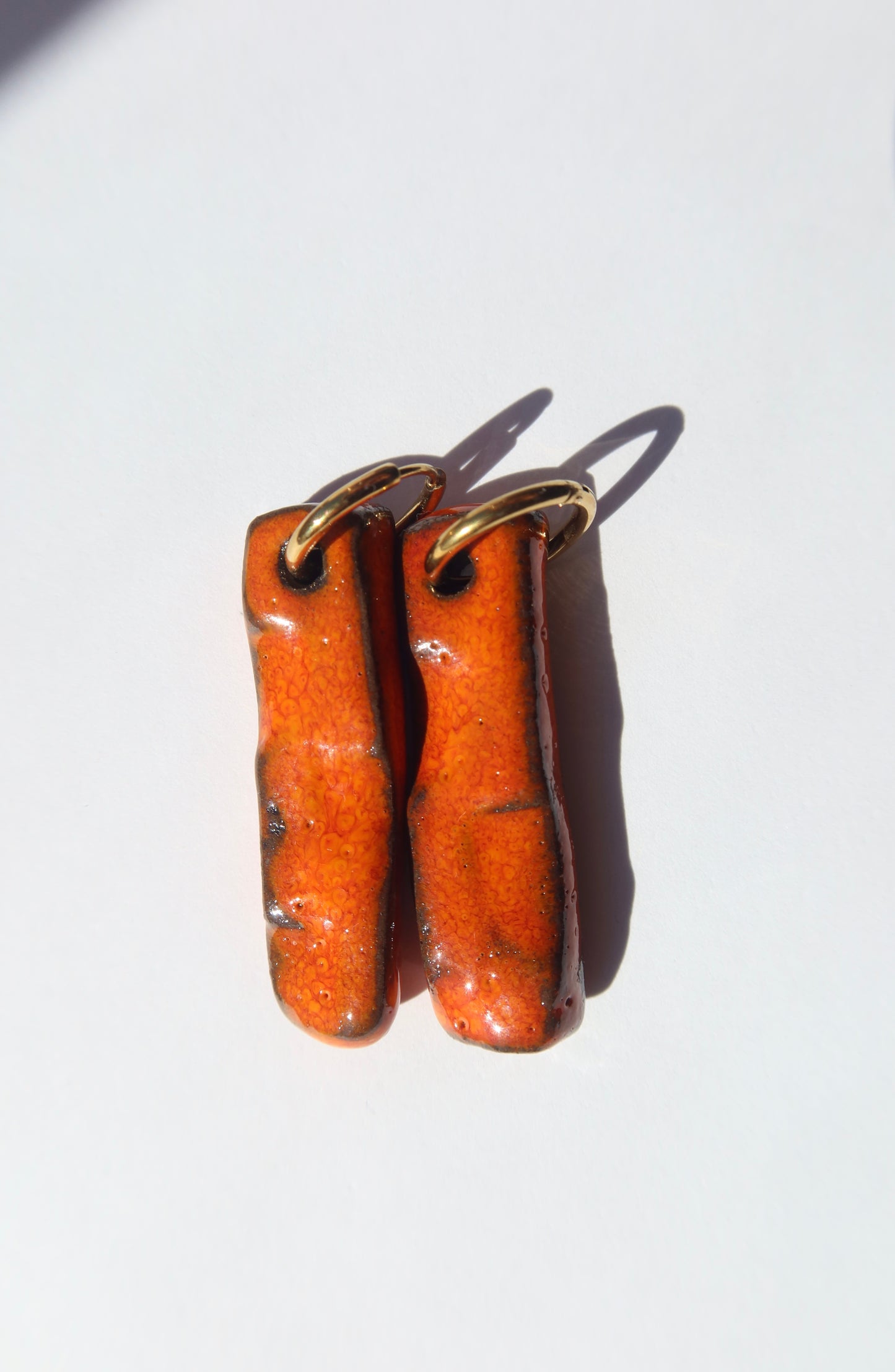 Penha handmade ceramic earrings in Volcano on Dark Clay — minimalist rectangular drop, sculpted clay, made in Lisbon Portugal by Jadeo Studio, silver and gold hoop